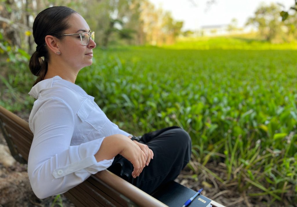 Woman sitting in wetland site looking contemplative